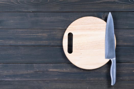 Close up kitchen knife and round cutting board on a wooden table