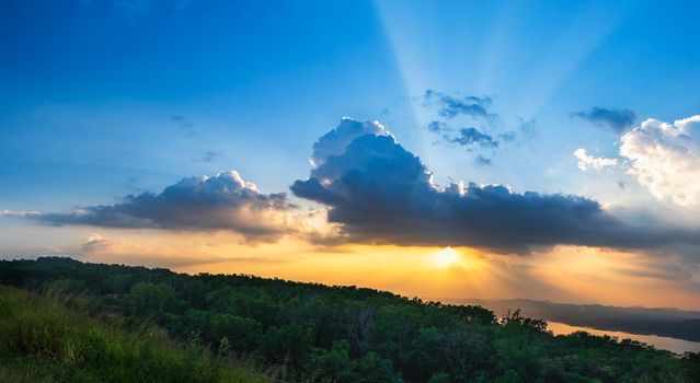 Sunset with ray light on clouds in a blue and orange sky in twilight time