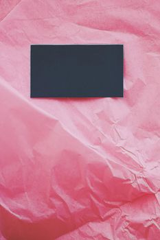 Black business card flatlay on pink tissue paper background, luxury branding flat lay and brand identity design for mockups