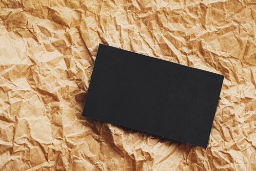 Black business card flatlay on brown parchment paper background, luxury branding flat lay and brand identity design for mockups