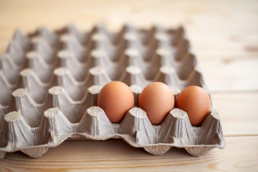 Several brown eggs lie in a row in a large cardboard bag, a chicken egg as a valuable nutritious product, a tray for carrying and storing fragile eggs