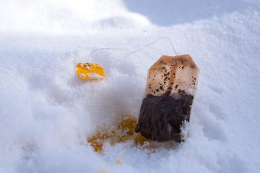 A used tea bag lies in the snow like rubbish and pollutes the environment