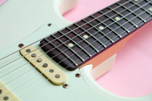 Detail of White Electric Guitar on a pink background.