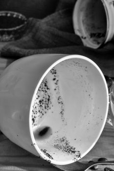 Side view of an empty coffee Cup with coffee stains on the bottom and an empty dirty coffee mug after finishing drinking. A dirty Cup and a Turk on a metal tray, on a wooden background. Copy space.