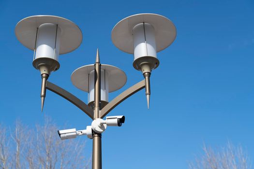 outdoor security camera on a lamppost against a blue sky. High quality photo