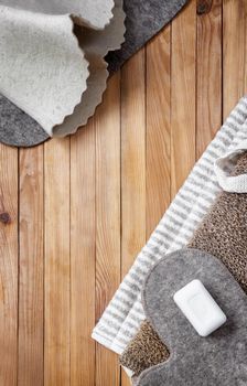 Accessories for visiting the bath or sauna on a wooden background: towel, bath mat, felt hat, washcloth, soap. Top view with copy space. Flat lay