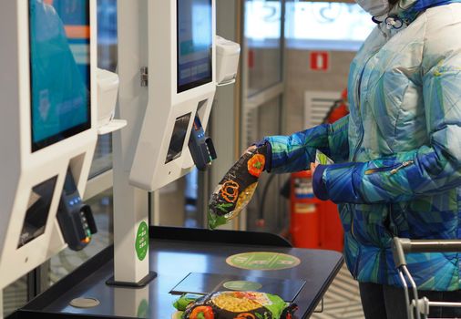 The latest Technologies. Self-service checkout in the supermarket. A woman buys groceries in a supermarket and pays for goods at the self-service checkout with a bank card.