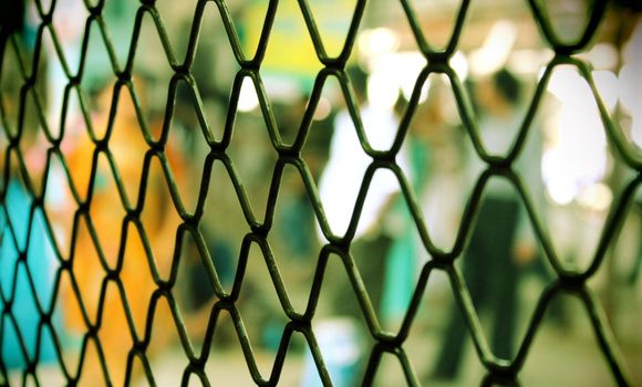 seamless metal mesh fence with colorful blur background and focus on fence.