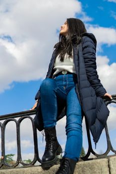 Young girl in blue jeans and white sweater with blue sky in the background