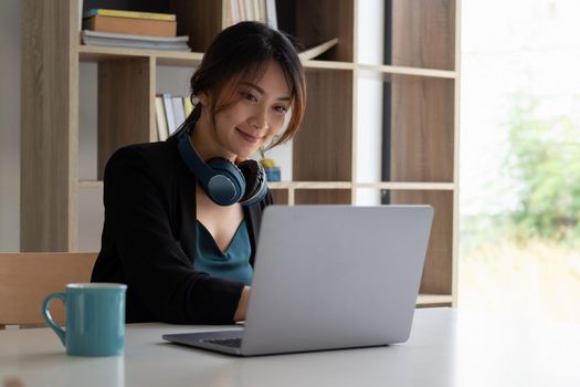 Portrait of asian woman studying online with laptop computer while sitting at the table and notebook at home.