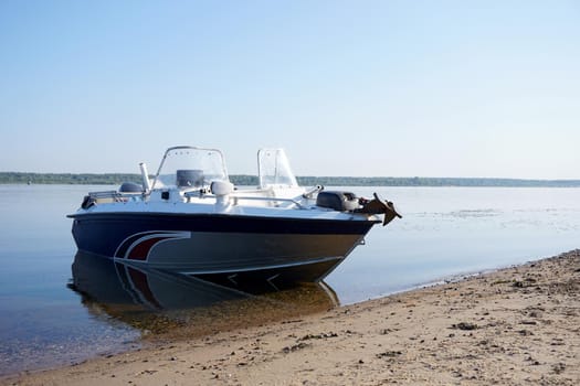 A motorboat stands on the sandy bank of the river without people. High quality photo