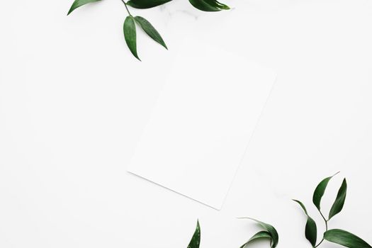 Blank white card, green leaves on white background as botanical frame flatlay, wedding invitation and holiday branding, flat lay design concept