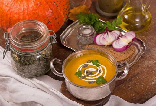 Bowl of pumpkin soup on rustic wooden background.