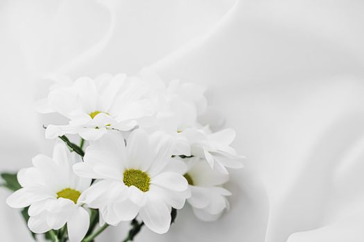 White daisy flowers on silk fabric as bridal flatlay background, wedding invitation and holiday branding, flat lay design concept