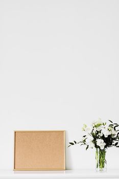 Golden horizontal frame and bouquet of fresh flowers on white furniture, luxury home decor and design for mockup creations