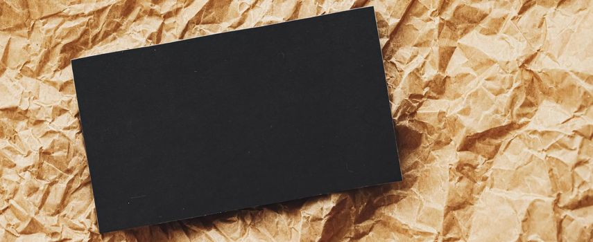 Black business card flatlay on brown parchment paper background, luxury branding flat lay and brand identity design for mockups