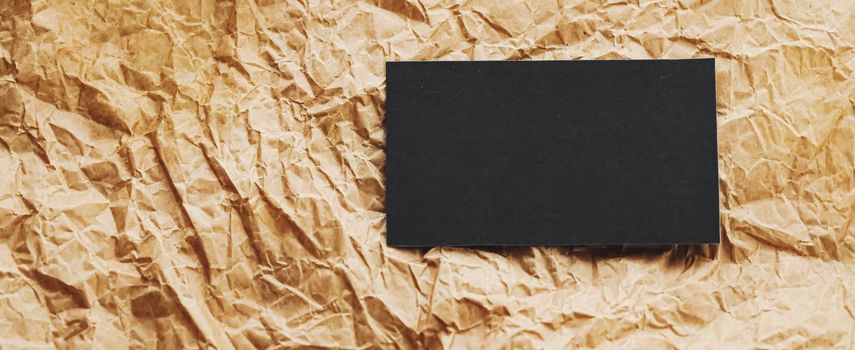 Black business card flatlay on brown parchment paper background, luxury branding flat lay and brand identity design for mockups