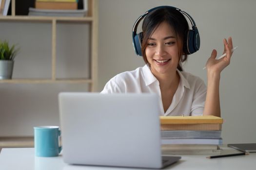 Asian woman wearing headphones study online watching webinar podcast on laptop listening learning education course conference calling, elearning concept.