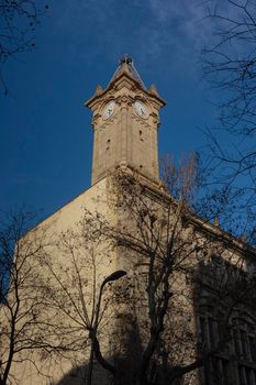 Tower with clock in a historic building in one of the streets of Barcelona in Spain.