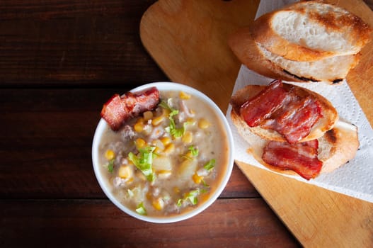 A bowl of homemade corn chowder soup with potatoes, carrots and croutons. Delicious cozy first courses, comfortable food.