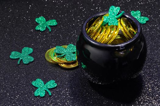 St Patrick's day gold coins and shamrock clovers with pot of gold on black