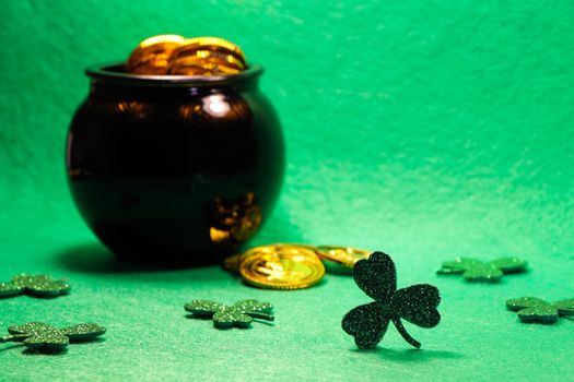 St Patrick's day shamrock clovers with coin filled pot of gold on green