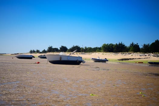 boats laying on the sand at lowtide on a sunny day with a blue cloudless sky on the isle of Ile de Ré