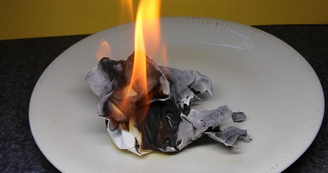 A match lights a ball of paper and it burns brightly