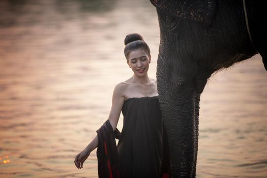 Portrait Of Young Woman Standing By Elephant In Forest