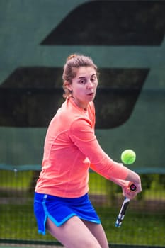 Young woman wearing blue skirt, pink top and tennis shoes during professional tennis match.