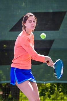 Young woman wearing blue skirt, pink top and tennis shoes during professional tennis match.