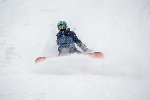 Person go down on a snowboard from the mountainside along a specially prepared track. They make mistakes and fall. Ski vacation. January, Logoisk, Belarus