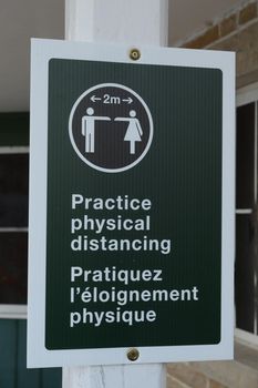 A closeup of a sign for informing the public about physical distancing practices.