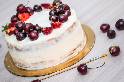 Cherries and strawberries with edible gold on top of cheesecake with coconut.