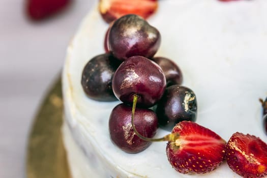 Cherries and strawberries with edible gold on top of cheesecake with coconut.