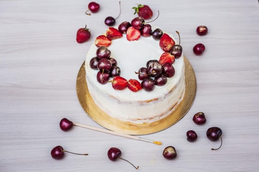 Cherries and strawberries with edible gold on top of cheesecake with coconut.