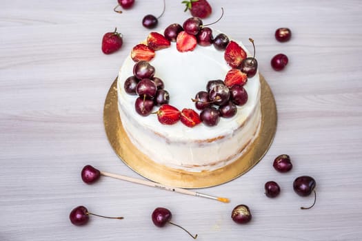 Cherries and strawberries with edible gold on top of cheesecake with coconut.