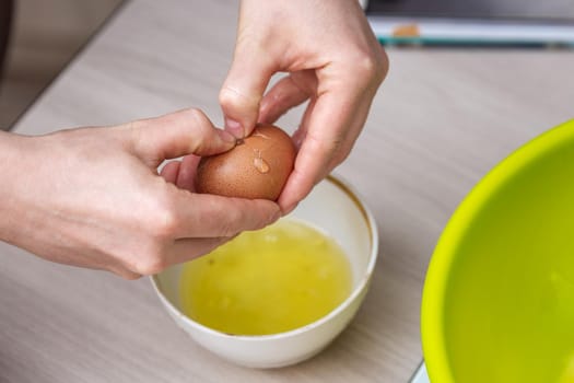 Close-up woman's hands break the egg and separate the white from the yolk.
