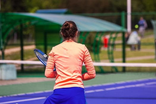 Young woman wearing blue skirt, pink top and tennis shoes during professional tennis match.