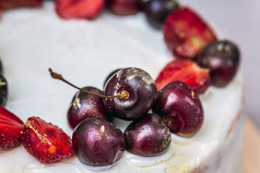 Cherries and strawberries with edible gold on top of cheesecake with coconut.