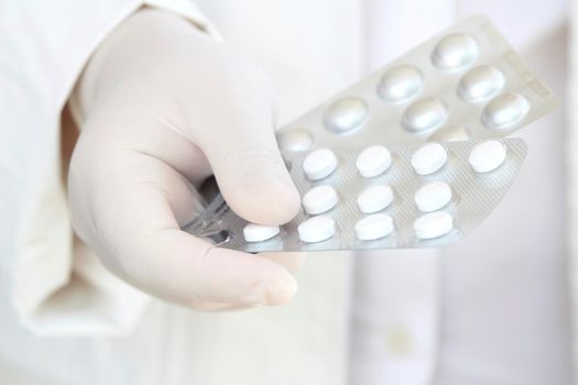 Male hand in white surgical glove holding pill blisters