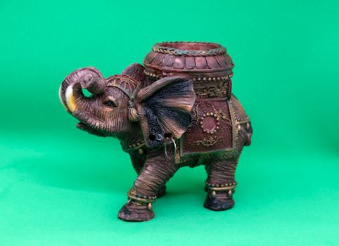 Figurine of an Indian elephant on a green background close-up. Candlestick in the shape of an Indian elephant.