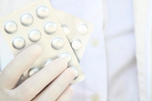 Male hand in white surgical glove holding pill blisters