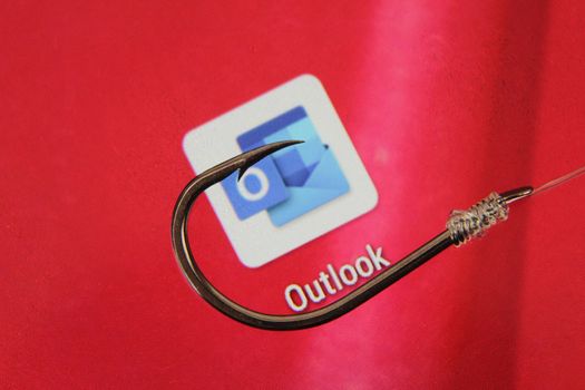 Madrid, Spain- May 10, 2010: Conceptual picture emulating phishing scam with a hook on Outlook icon on red screen