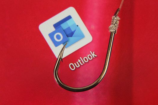 Madrid, Spain- May 10, 2010: Conceptual picture emulating phishing scam with a hook on Outlook icon on red screen