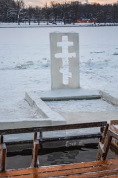 Cross near ice bath. Winter Baptism in Minsk Belarus. Baptismal bathing - a folk tradition that exists in Russia, Belarus, Ukraine. Bathing in the ice hole. Plunge into the ice water.