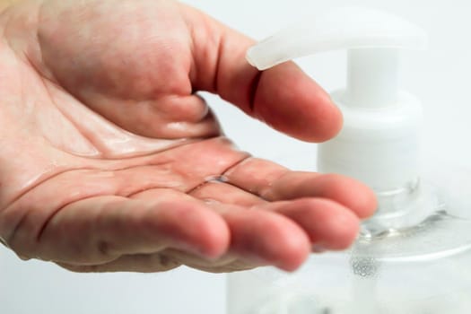 Hydroalcoholic gel bottle pouring gel into a hand on white background