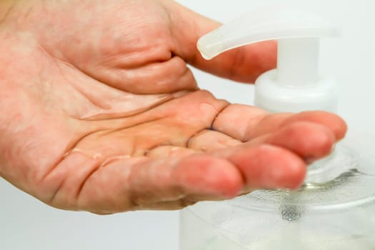 Hydroalcoholic gel bottle pouring gel into a hand on white background