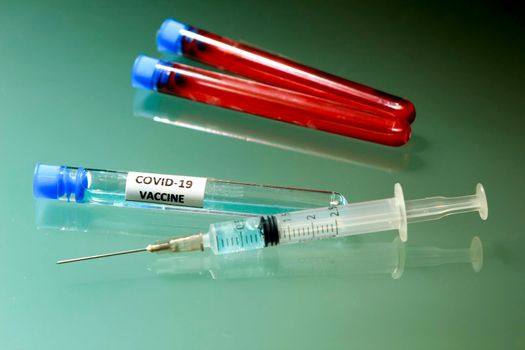 Syringe next to test tube with vaccine for Covid-19 virus