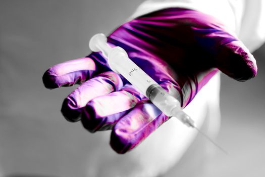 Male hand in surgical glove holding a syringe